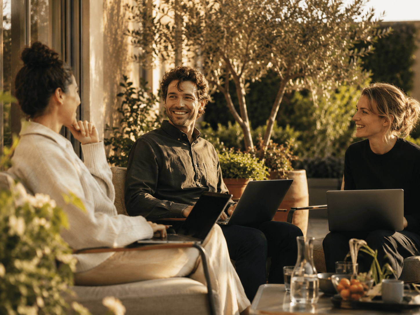 A small team working together with laptops in warm natural light